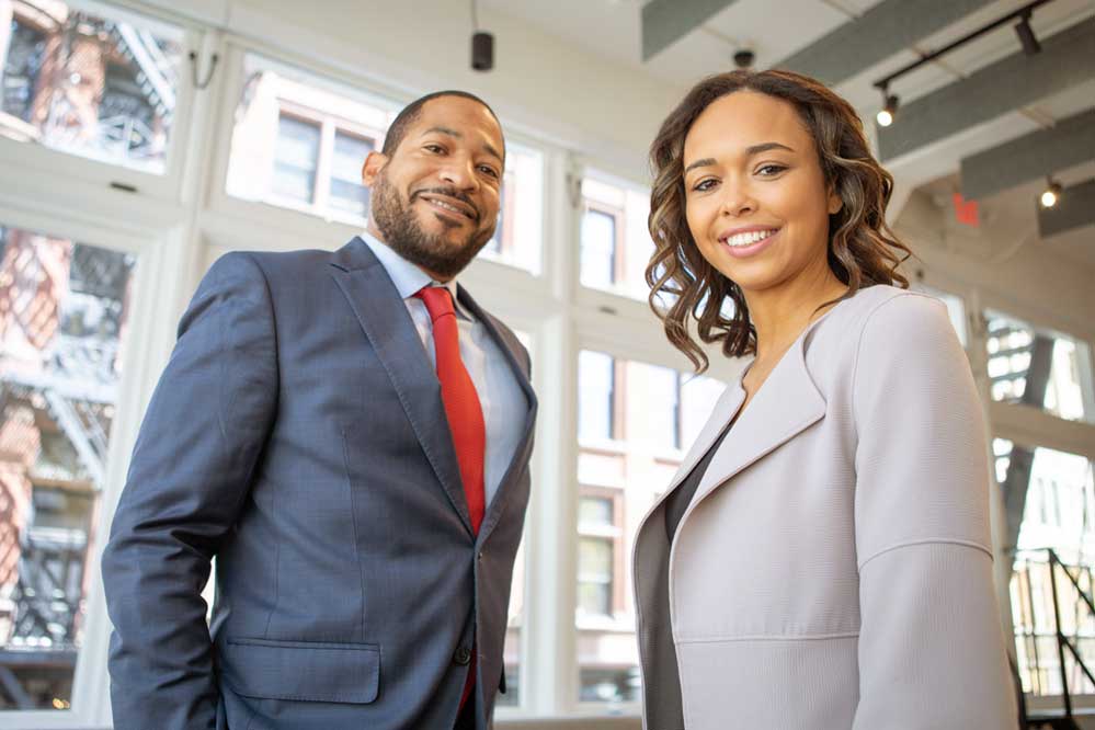 Man and Woman smiling with suits inside building