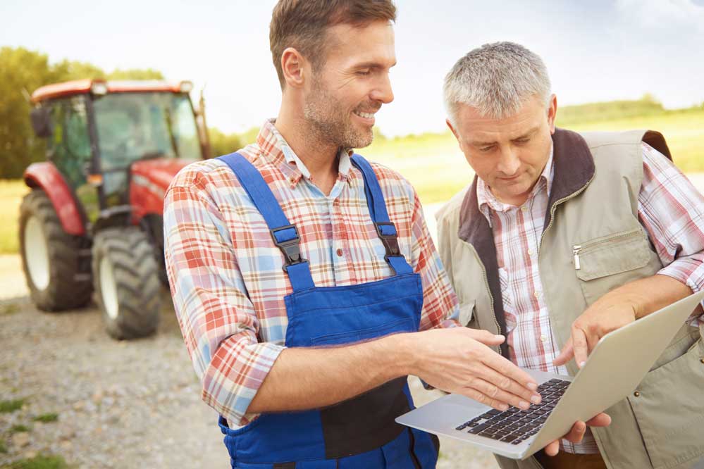 Man explaining farm manager the benefits of IoT in agriculture with a laptop