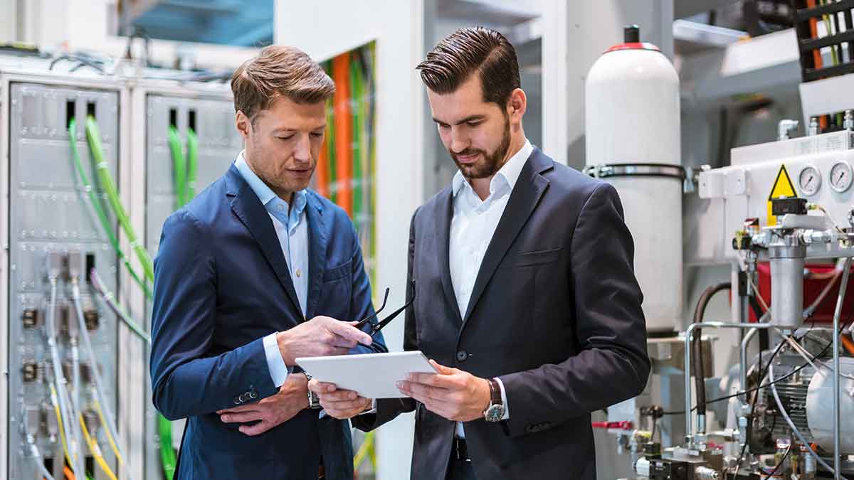 Two businessmen remotely monitoring their machines after implementing Industrial IoT solutions